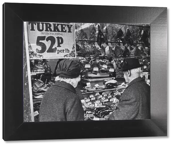 Couple looking at meat products on display in butchers shop, Cardiff, Wales