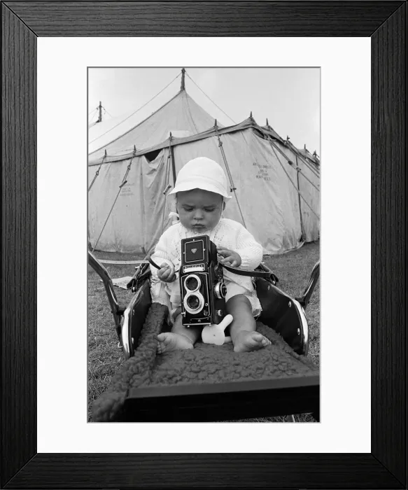 Framed Print : A baby sitting with a Rolleiflex camera at Skelton annual baby show. Circa 1973