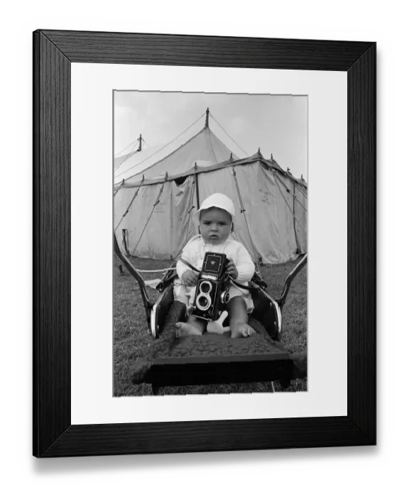 Framed Print : A baby sitting with a Rolleiflex camera at Skelton annual baby show. Circa 1973