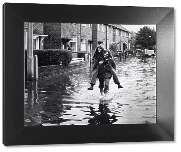 Residents of Brunswick Road in Altrincham wade through deep water on the street after