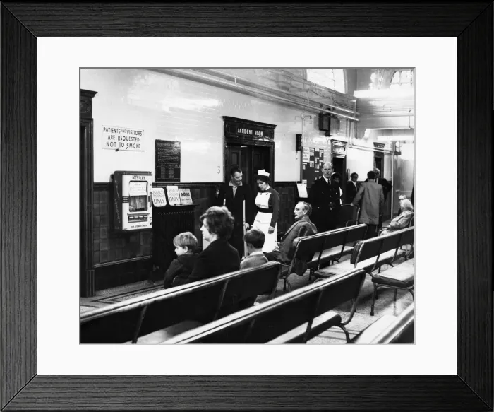 Framed Print : Sister Marjorie Cook talks to an out patient in the hall at at Ancoats Hospital in Mill