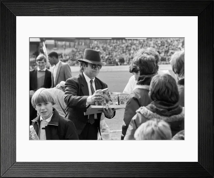 Framed Print : Pop star and Watford FC Chairman, Elton John, handing out Easter eggs to fans Framed Print : Pop star and Watford FC Chairman, Elton John, handing out Easter eggs to fans