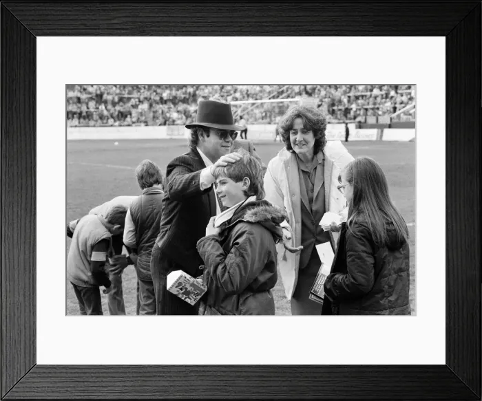 Framed Print : Pop star and Watford FC Chairman, Elton John, handing out Easter eggs to fans