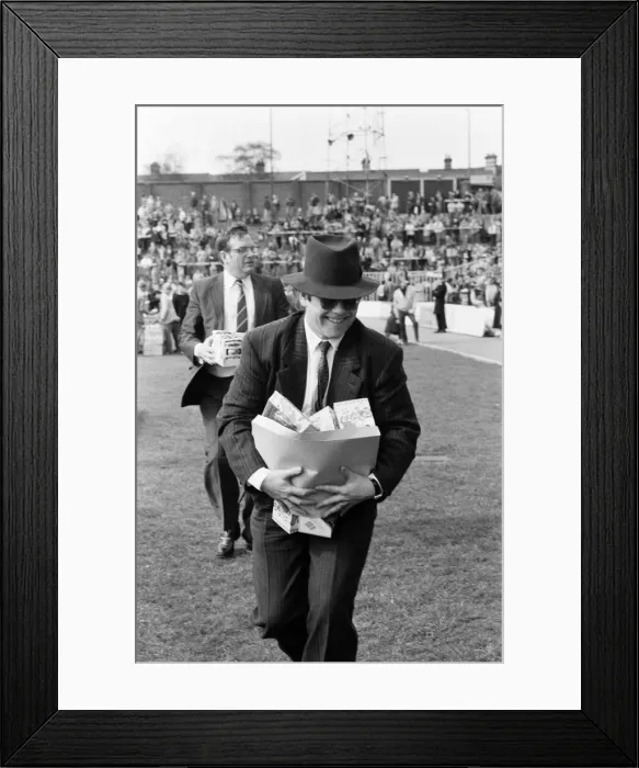 Framed Print : Pop star and Watford FC Chairman, Elton John, handing out Easter eggs to fans Framed Print : Pop star and Watford FC Chairman, Elton John, handing out Easter eggs to fans