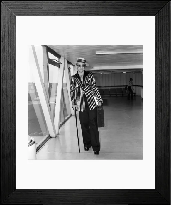 Framed Print : Pop star Elton John wearing a hat trimmed with flowers and feathers Framed Print : Pop star Elton John wearing a hat trimmed with flowers and feathers