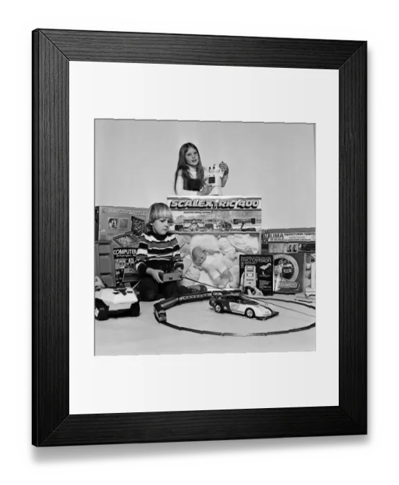 Framed Print : A young boy and girl with a selection of childrens toys for Christmas. December 1980