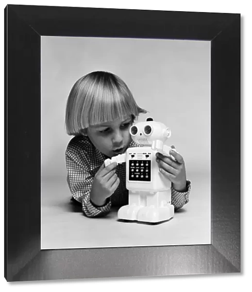 A young boy playing with a Computer48 toy robot. December 1980
