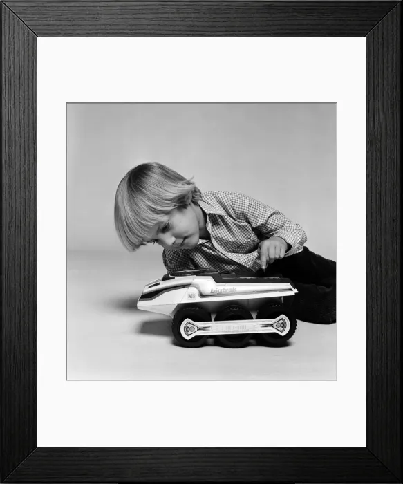 Framed Print : A young boy playing with a Big Trak toy, a programmable electric vehicle created by Framed Print : A young boy playing with a Big Trak toy, a programmable electric vehicle created by