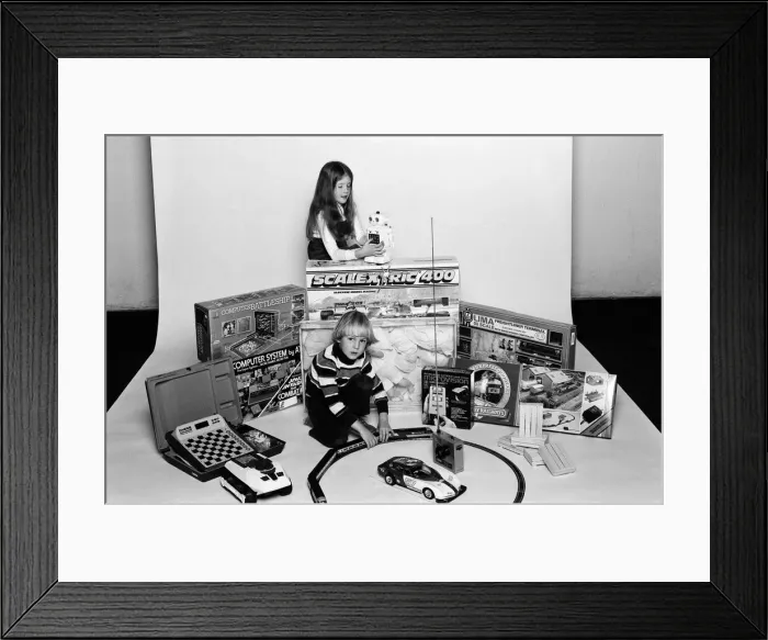 Framed Print : A young boy and girl with a selection of childrens toys for Christmas. December 1980
