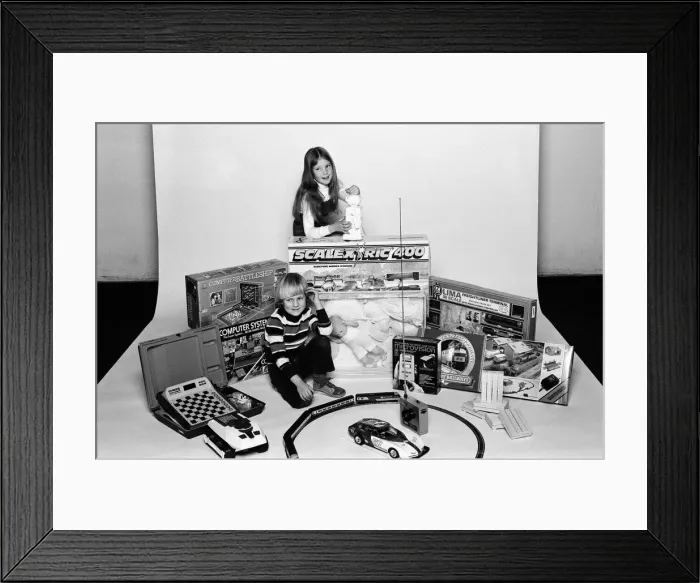 Framed Print : A young boy and girl with a selection of childrens toys for Christmas. December 1980