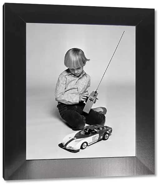 A young boy playing with a remote control car. December 1980