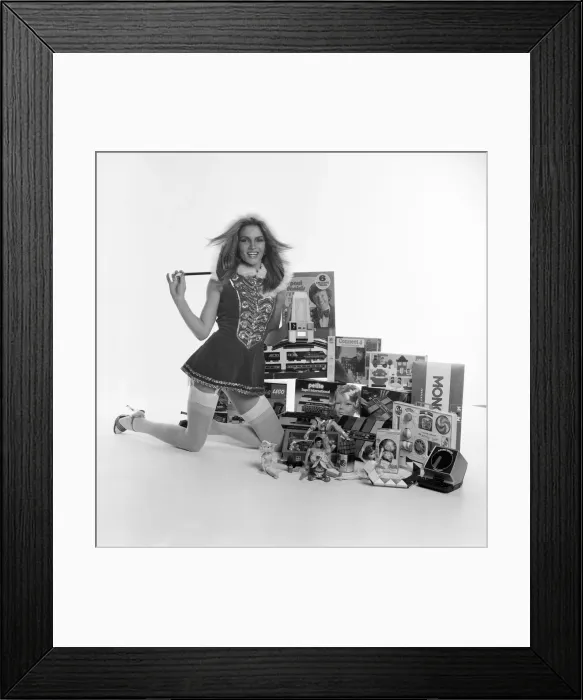 Framed Print : A female model in a santa outfit with a selection of childrens toys for Christmas Framed Print : A female model in a santa outfit with a selection of childrens toys for Christmas