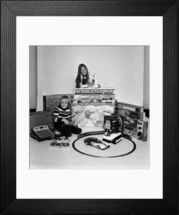 Framed Print : A young boy and girl with a selection of childrens toys for Christmas. December 1980