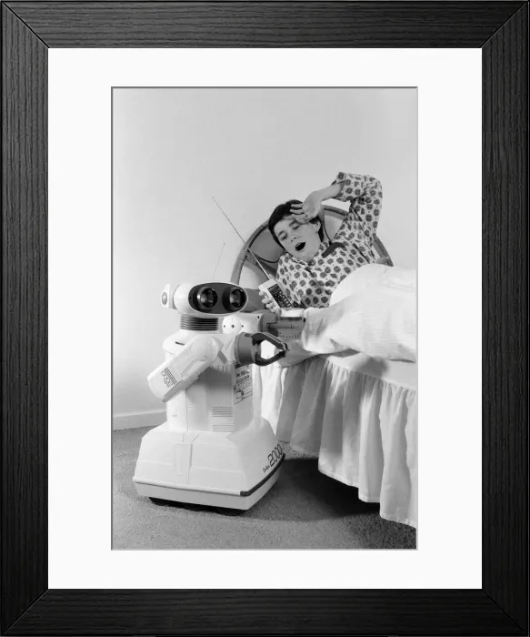 Framed Print : A young boy in bed being woken by an Omnibot 2000 toy robot. 21st October 1986 Framed Print : A young boy in bed being woken by an Omnibot 2000 toy robot. 21st October 1986