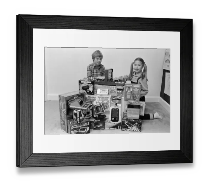 Framed Print : Two lucky children surrounded by a selection of electronic games available in the shops Framed Print : Two lucky children surrounded by a selection of electronic games available in the shops