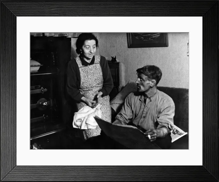 Framed Print : Husband Tom, home from the pit, likes a look at the paper as his wife waits to dish up