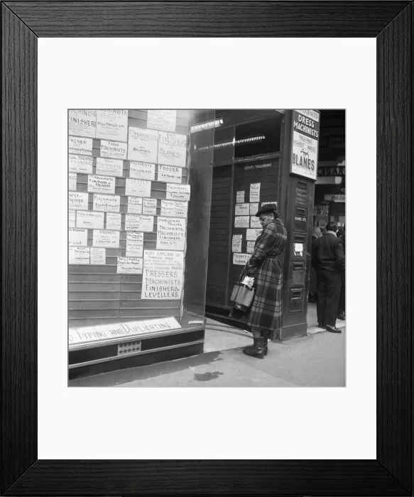 Framed Print : A woman looks in the window of an un-named East End of London employment agency which Framed Print : A woman looks in the window of an un-named East End of London employment agency which