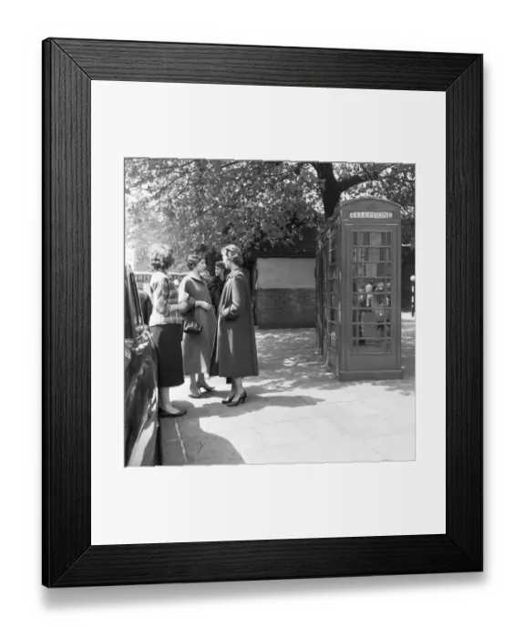 Framed Print : awaiting their turn. Ladies queue to use the public telephone box close to the Tower of