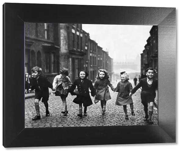 Children of Bengel Street holding hands as they walk up the terraced street from school