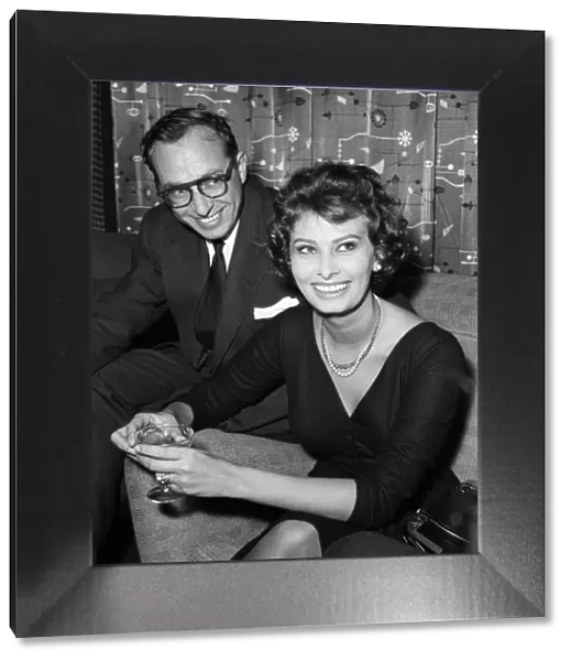Sophia Loren (with an un-named man) pictured sitting in a chair at London Airport