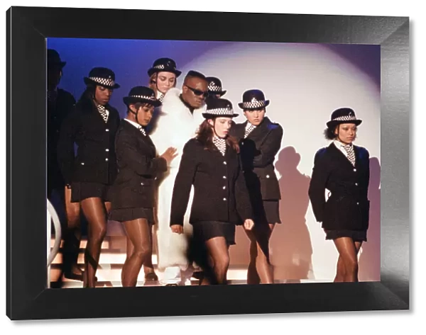 Mark Morrison flanked by dancers dressed as policewomen