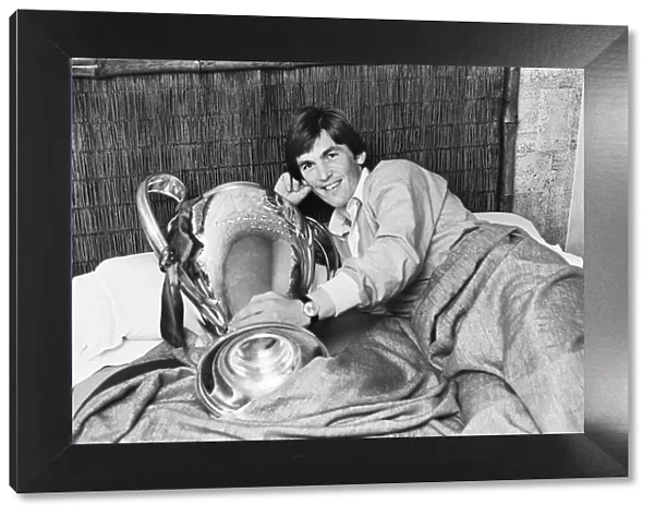 Liverpool footballer Kenny Dalglish poses in bed with the European Cup trophy the day