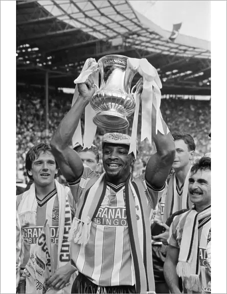 Cyrille Regis holds the FA Cup aloft after his team Coventry beat Tottenham Hotspur 3-2