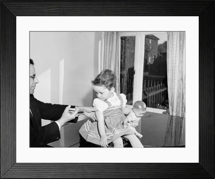 Framed Print : A young patient looks on with trepidation whilst having her polio vaccination Framed Print : A young patient looks on with trepidation whilst having her polio vaccination