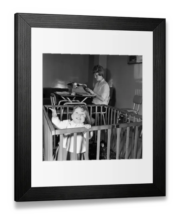 Framed Print : 9 month old Jane Turnock plays happily in her play pen as her mothers works away in