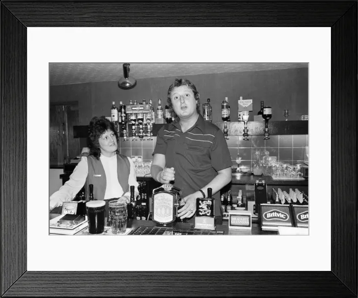 Framed Print : British dart player Eric Bristow pictured at the pub, serving drinks behind the bar