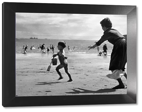 Three year old John Cromwell running away from his mother on the beach at Barry island