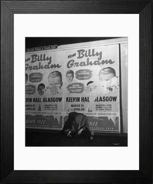 Framed Print : A sleeping drunk sits underneath a defaced poster of Billy Graham in Glasgow ahead of his Framed Print : A sleeping drunk sits underneath a defaced poster of Billy Graham in Glasgow ahead of his