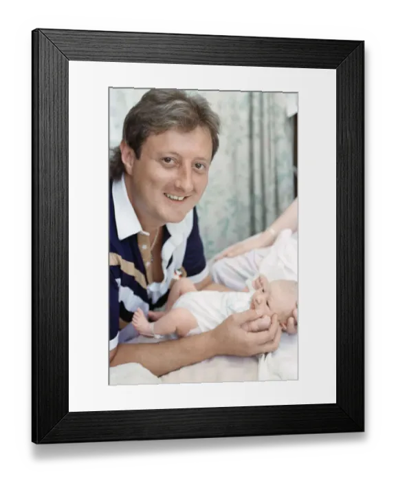 Framed Print : British darts player Eric Bristow poses at home with his new born baby girl who has been Framed Print : British darts player Eric Bristow poses at home with his new born baby girl who has been