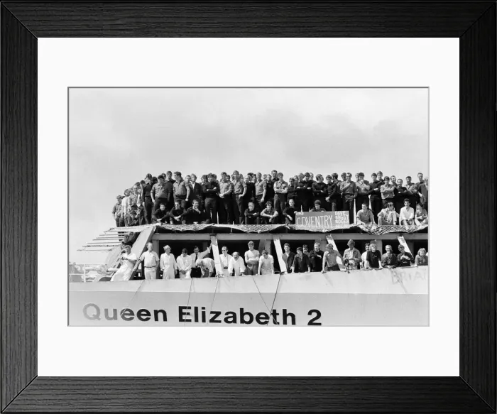 Framed Print : QE2 returns home to Southampton. Union Jacks are festooned on cars, draped on shoulders