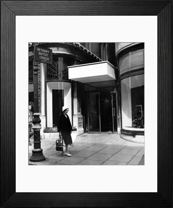 Framed Print : The new and old. Outside the entrance to the department store still stands the sign