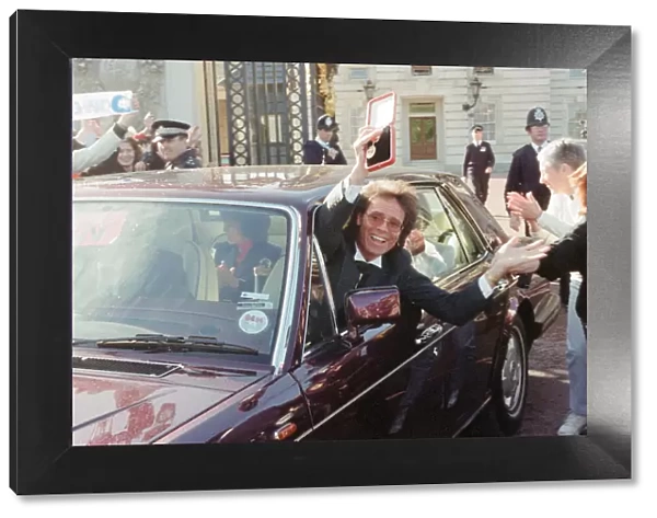 A newly-knighted Sir Cliff Richard leaves Buckingham Palace waving his gong aloft