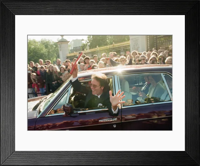 Framed Print : A newly-knighted Sir Cliff Richard leaves Buckingham Palace waving his gong aloft