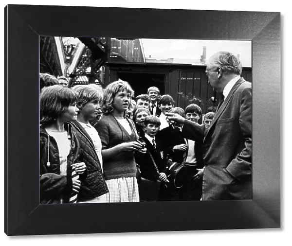 Prime Minister Harold Wilson pauses to chat with a group of children who met his train at