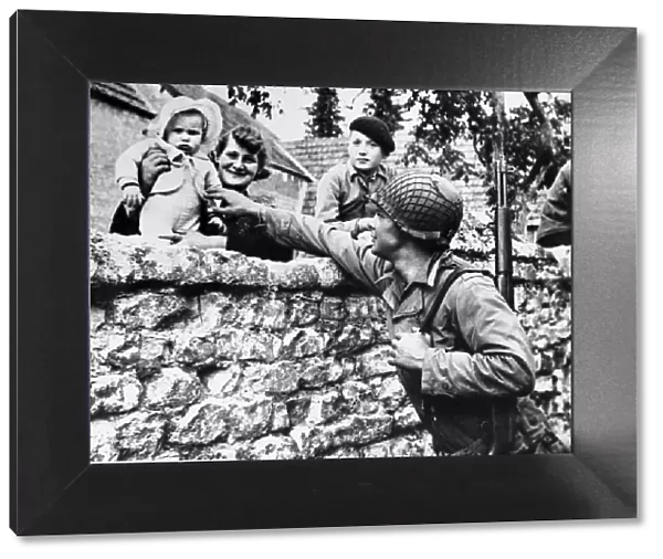 French civilians lean over their garden wall to greet an american solider of the allied