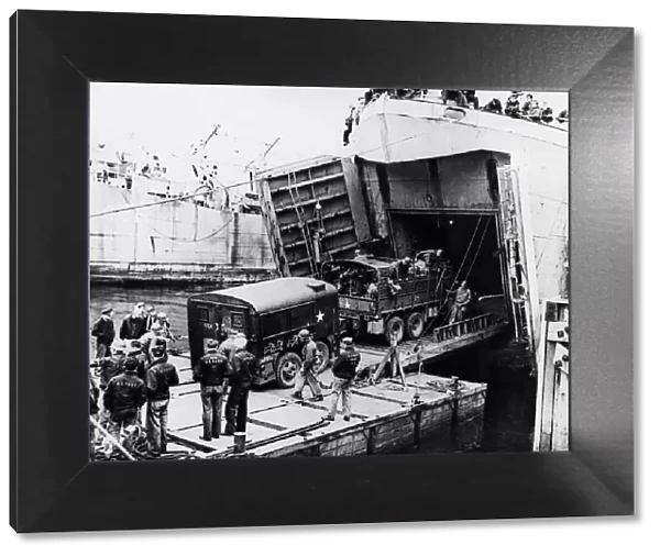 A heavy truck pulls a field kitchen up the bow ramp of an LST (Landing Ship Tank
