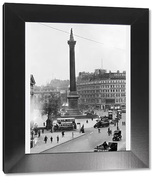 Trafalgar Square in London. Buses carry passengers around the square and Nelson