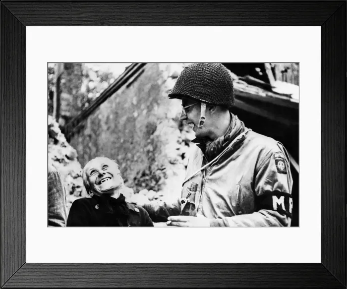 Framed Print : An American troop shares a joke with a civilian while on duty. 22nd June 1944 Framed Print : An American troop shares a joke with a civilian while on duty. 22nd June 1944