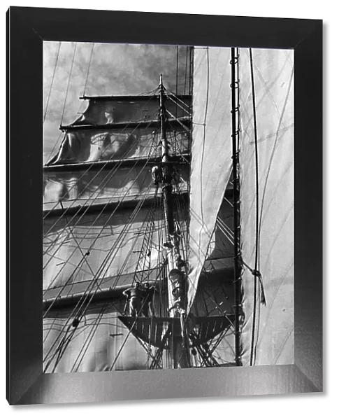 Men look down from the mast of a tall ship. Circa 1925