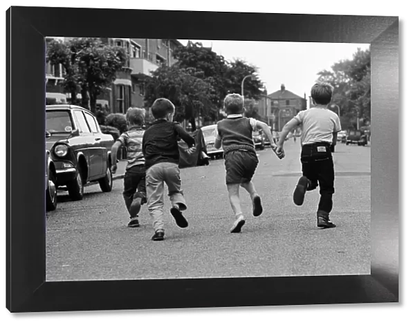 Children playing in the streets, running down the road. June 1964