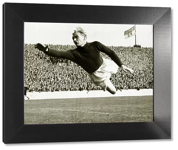 Bert Trautmann of Manchester City in full flight as he leaps across to cover a