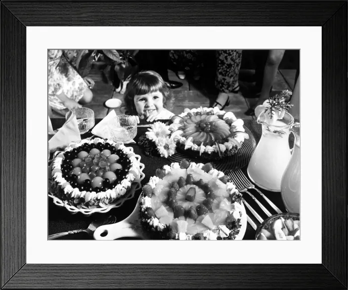 Framed Print : A young girl looking at a table with cakes. 1970 Framed Print : A young girl looking at a table with cakes. 1970