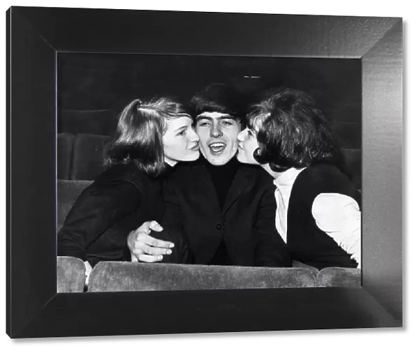 George Harrison of The Beatles is kissed by two female fans