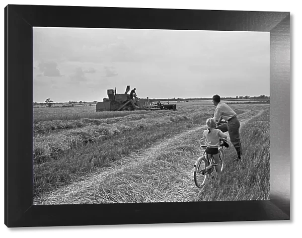 Father and daughter out for a Sunday bike ride watches the farmers of Stansted gather in