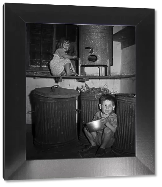 Children playing indoors by dustbins in a house in Hull. 9th July 1953