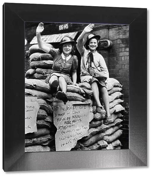 East End Ritz hotel, two women sitting on sand bags waving to the camera